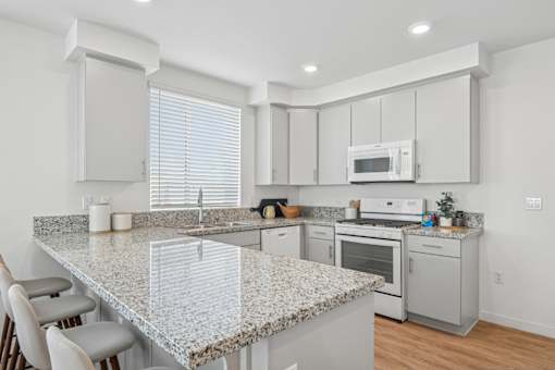 Kitchen with island seating and granite counters at Altitude Apartments, Moreno Valley
