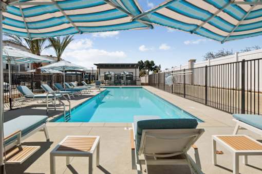 Swimming pool with striped shade umbrellas and lounge chairs at Altitude Apartments, Moreno Valley, California