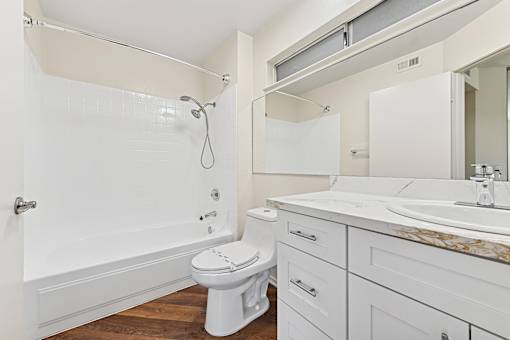 Bathroom inside Cielo apartment home with plank flooring, shaker cabinets, and quartz countertops. Spacious shower/tub and plenty of storage