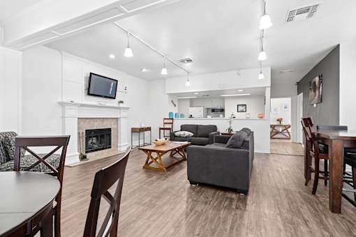Community clubhouse at California Place Apartments with wood flooring, high ceilings, and cozy seating area next to fireplace