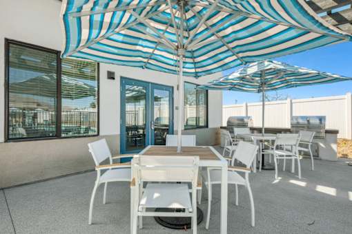 Patio area with grills and striped umbrellas at Altitude Apartments, California, 92553