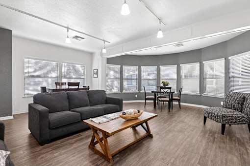 Community clubhouse at California Place Apartments with wood flooring, high ceilings, and cozy seating area next to fireplace