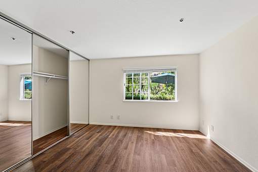 Oversized bedroom inside Cielo apartment home with plank flooring, large closet with mirrored doors, and large windows allowing for gorgeous natural lighting.