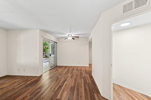 Oversized living area in Cielo apartment hime with plank flooring large windows, and sliding doors leading to private patio. Open concept floor plan leading to dining area and kitchen.