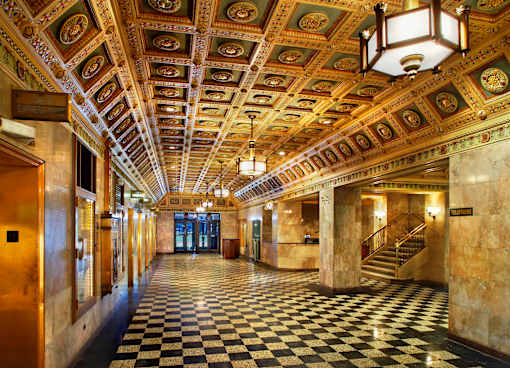 A long hallway with a checkered floor and a ceiling with gold trim.