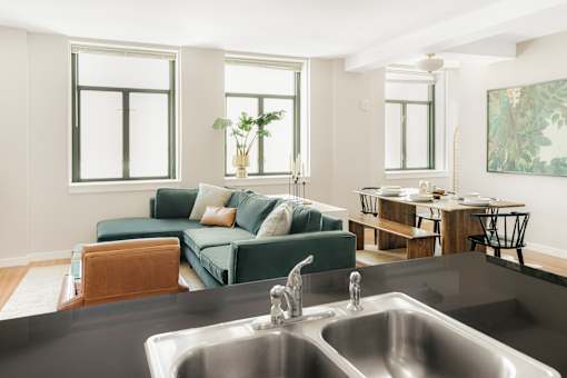 A modern kitchen with a green couch and a wooden table.