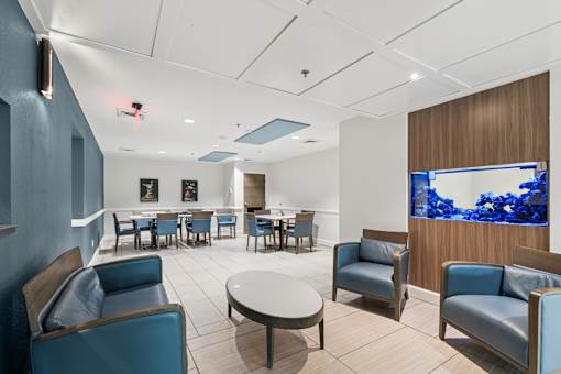A room with blue chairs and a television displaying blue flowers at Hampton Apartments, Clearwater, FL, 33759