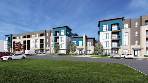 A modern apartment complex with two cars parked in front.