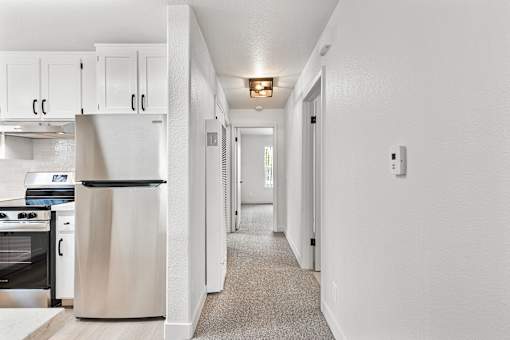 A kitchen with a refrigerator, oven, and cabinets.