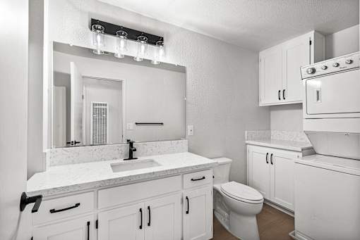 A white bathroom with a toilet, sink, and mirror.