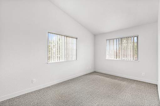 A room with two windows and carpeted floor.