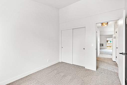 A white room with a carpeted floor and a white door.