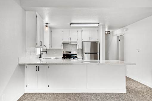A modern kitchen with white cabinets and stainless steel appliances.