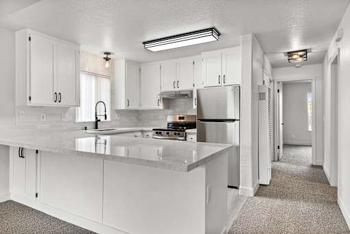 A kitchen with white cabinets and a quartz countertop.