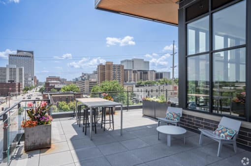 A patio with a table and chairs overlooking a city skyline.