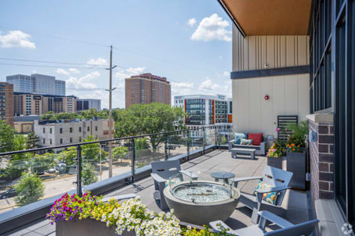 A balcony with a table and chairs overlooking a cityscape.