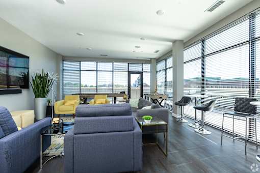 a living room with blue couches and chairs and a large window with a view at 1400 Russell Apartments, Saint Louis, Missouri
