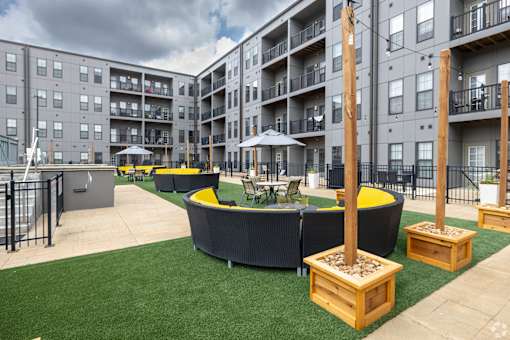 an outdoor lounge area with tables and chairs in front of an apartment building at 1400 Russell Apartments, Missouri