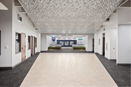 an empty hallway in a building with white walls and tiled floors