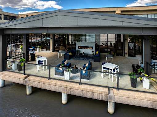 A patio with chairs and tables overlooking a body of water. at The Residences at Tesson Ridge Apartments, Saint Louis, MO