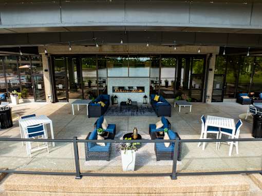 A patio with blue chairs and a table with a vase of flowers on it. at The Residences at Tesson Ridge Apartments, Saint Louis, 63128
