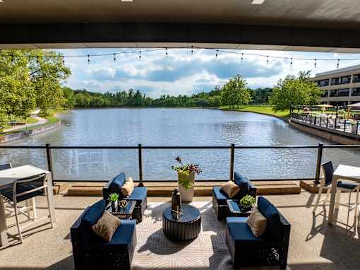 A patio with blue couches overlooks a lake. at The Residences at Tesson Ridge Apartments, Saint Louis
