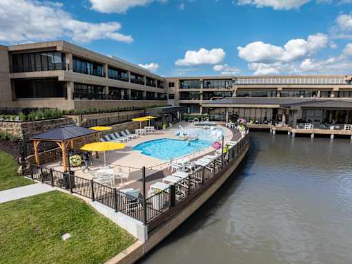 A pool surrounded by a fence and umbrellas. at The Residences at Tesson Ridge Apartments, Saint Louis, MO, 63128
