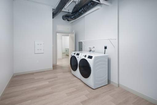 A white washing machine is in a room with wooden floors. at The Residences at Tesson Ridge Apartments, Saint Louis