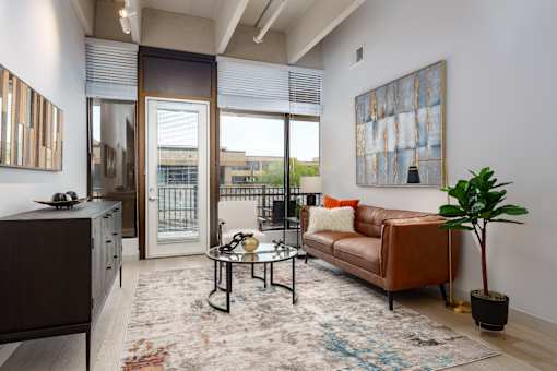 A living room with a brown couch, a coffee table, and a large painting on the wall. at The Residences at Tesson Ridge Apartments, Missouri, 63128
