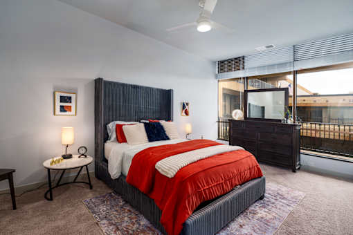 A bedroom with a large bed and a window overlooking a balcony. at The Residences at Tesson Ridge Apartments, Saint Louis, Missouri