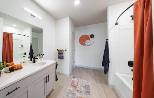 A bathroom with a white sink and orange shower curtain. at The Residences at Tesson Ridge Apartments, Saint Louis, MO