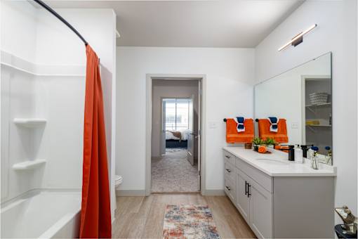 A bathroom with a white vanity and a red shower curtain. at The Residences at Tesson Ridge Apartments, Saint Louis, Missouri