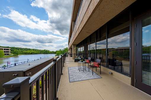 A patio with a table and chairs overlooking a river. at The Residences at Tesson Ridge Apartments, Missouri
