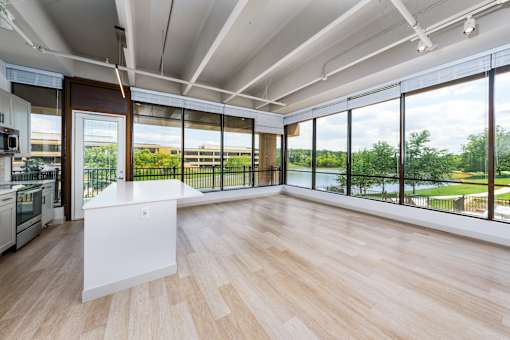 A kitchen with a white island in the middle of a room with wooden floors and a large window. at The Residences at Tesson Ridge Apartments, Missouri, 63128