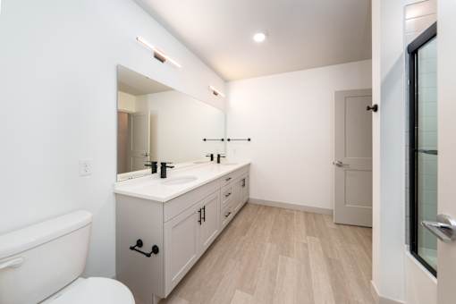 A white bathroom with a wooden floor and a white toilet. at The Residences at Tesson Ridge Apartments, Saint Louis, Missouri