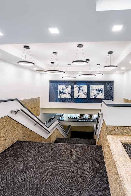 A staircase with a carpeted runner and a wall-mounted light fixture above it. at The Residences at Tesson Ridge Apartments, Missouri, 63128