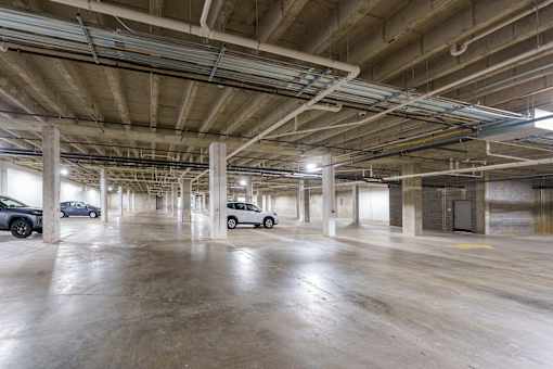 A spacious parking garage with concrete floors and multiple cars parked. at The Residences at Tesson Ridge Apartments, Saint Louis, MO