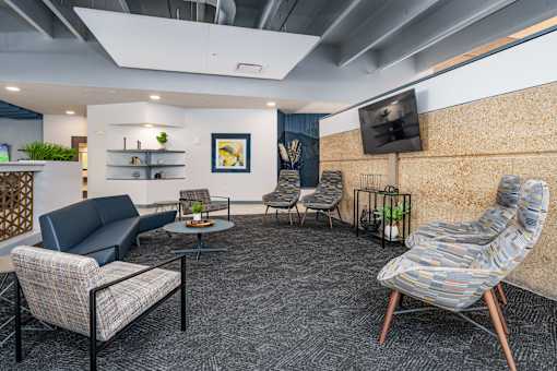 A modern living room with a grey carpet and a stone patterned chair. at The Residences at Tesson Ridge Apartments, Saint Louis, MO