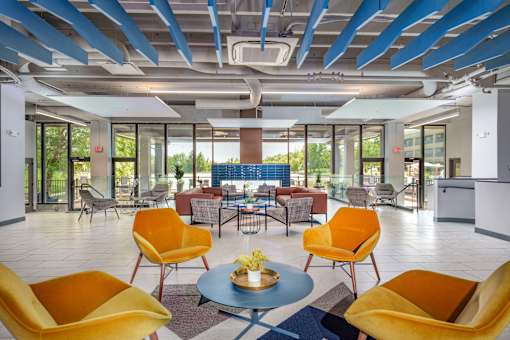 A modern room with yellow chairs and a blue table. at The Residences at Tesson Ridge Apartments, Saint Louis, MO
