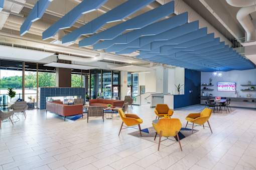 A modern open space with yellow chairs and a blue ceiling. at The Residences at Tesson Ridge Apartments, Saint Louis, 63128
