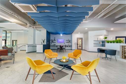 A modern living room with a blue ceiling and yellow chairs. at The Residences at Tesson Ridge Apartments, Missouri