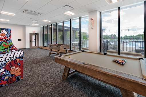A billiard table in a room with a pool table poster on the wall. at The Residences at Tesson Ridge Apartments, Missouri