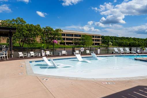 A large outdoor swimming pool with a water slide and lounge chairs. at The Residences at Tesson Ridge Apartments, Saint Louis, Missouri