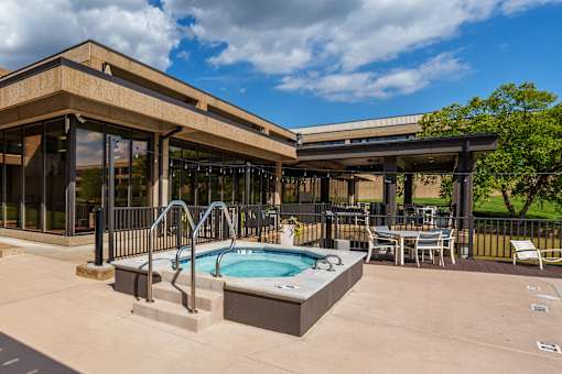 A hot tub is in the middle of a patio with a table and chairs. at The Residences at Tesson Ridge Apartments, Saint Louis, 63128