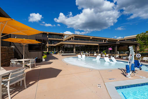 A sunny day at the pool with chairs and umbrellas. at The Residences at Tesson Ridge Apartments, Saint Louis, Missouri