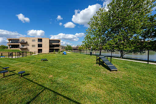 A grassy field with picnic tables and a building in the background. at The Residences at Tesson Ridge Apartments, Saint Louis