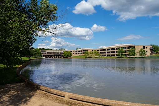 A serene lake with a building in the background. at The Residences at Tesson Ridge Apartments, Saint Louis, MO, 63128