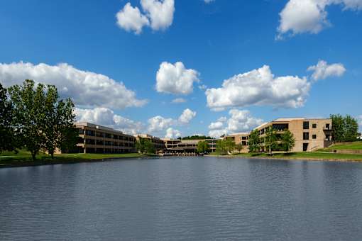 A large body of water with a building in the background and trees on the left. at The Residences at Tesson Ridge Apartments, Saint Louis