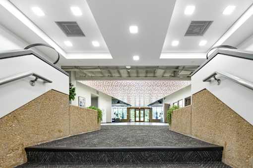 A modern building with a black carpeted staircase leading to a brightly lit hallway. at The Residences at Tesson Ridge Apartments, Missouri