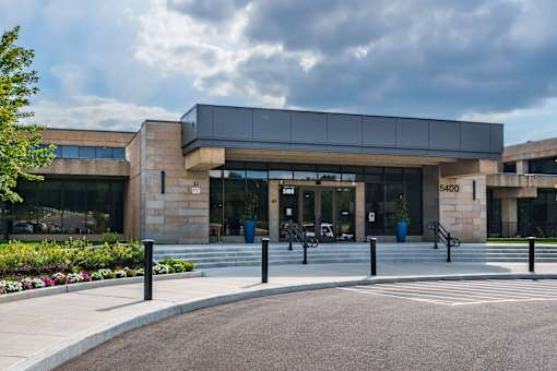 A modern building with a glass entrance and a stone facade. at The Residences at Tesson Ridge Apartments, Saint Louis, MO